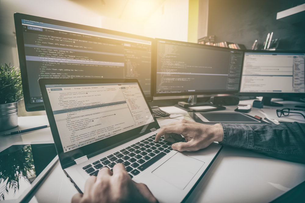 man coding a wordpress site on multiple monitors