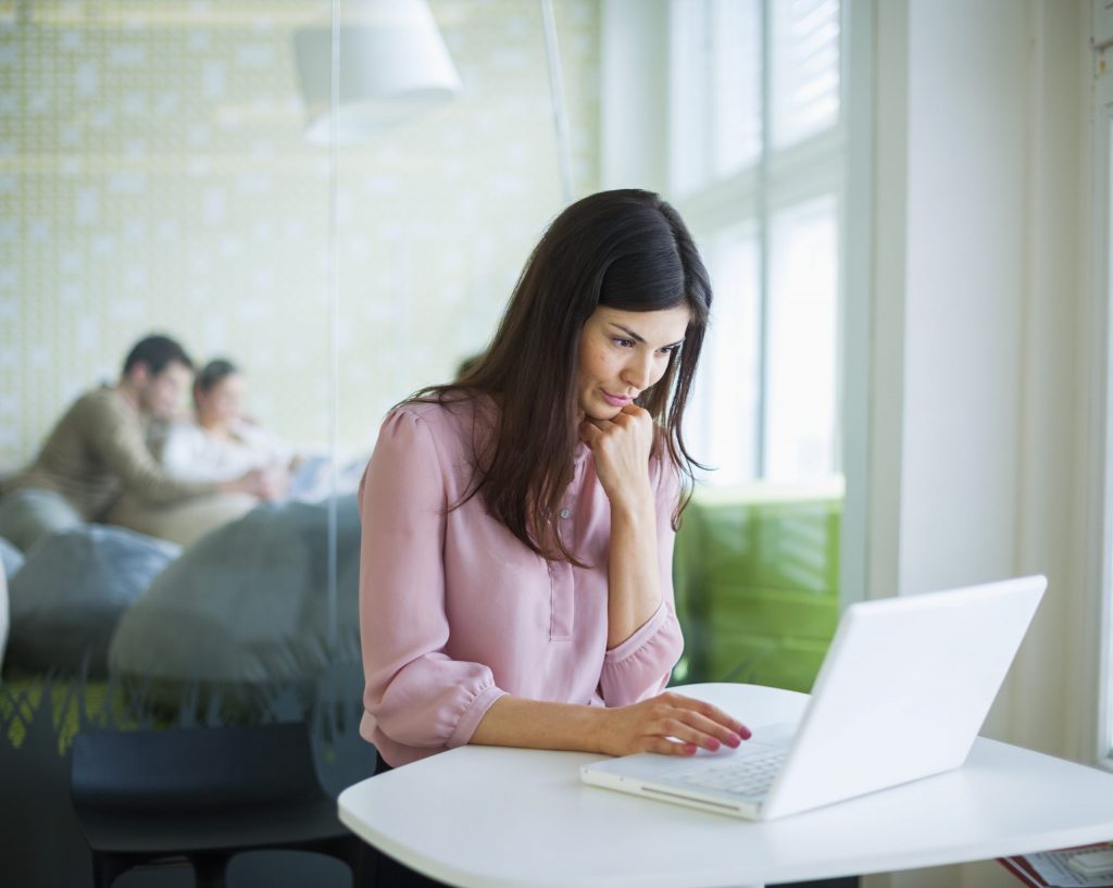 Young businesswoman using laptop at office table to update her wordpress theme
